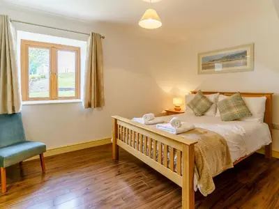a bedroom with a bed and a chair and a window at Cwmhyfryd in Llanllwchaiarn