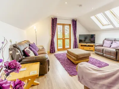 a living room with couches and a tv at Cwmhyfryd in Llanllwchaiarn