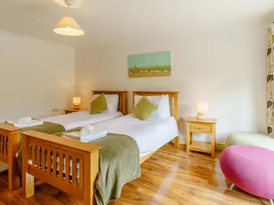 a bedroom with two beds and a chair at Cwmhyfryd in Llanllwchaiarn