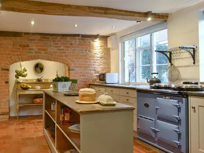 a large kitchen with a brick wall at Friary Cottage in Ludlow