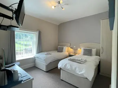 a hotel room with two beds and a window at Bwch yn Uchaf B&B in Llanuwchllyn