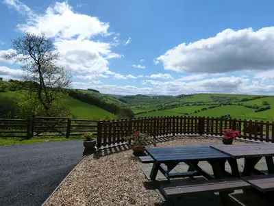 a picnic table on the side of a road with a fence at Beacons View Farm Cottages in Merthyr Cynog
