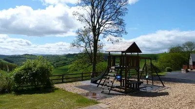a playground with a slide and a tree at Beacons View Farm Cottages in Merthyr Cynog