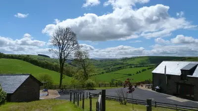 a view of a farm with green hills and clouds at Beacons View Farm Cottages in Merthyr Cynog