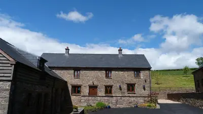 a large stone house with a black roof at Beacons View Farm Cottages in Merthyr Cynog