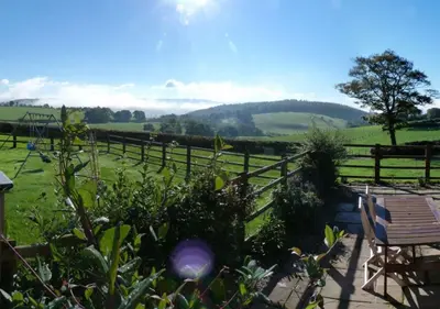 a garden with a bench and a fence and a field at Beudy Bach in Lampeter