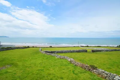 a stone wall in front of the ocean at Beudy Taicroesion in Barmouth