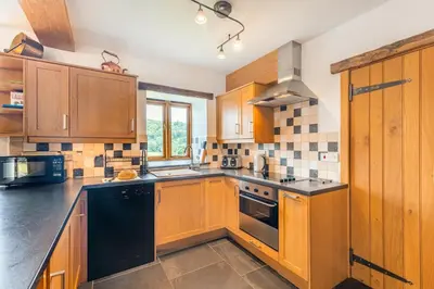 a kitchen with wooden cabinets and black appliances at 2 Bed in Bala oc-82768 in Llandderfel