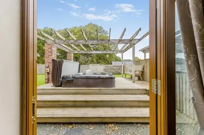 a door to a patio with a hot tub on a deck at 4 Bed in Builth Wells oc-39461 in Builth Wells