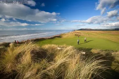 two people playing golf on a golf course next to the ocean at 2 Bed in Aberdyfi oc-78258 in Pennal