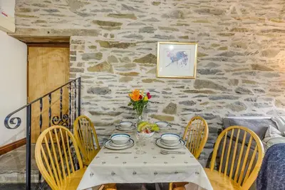 a dining room with a table with chairs and a stone wall at 2 Bed in Builth Wells oc-39471 in Builth Wells