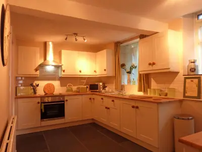 a kitchen with white cabinets and a stove top oven at Drws y Nant in Dolgellau