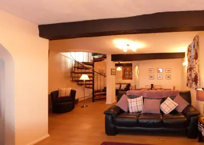a living room with a leather couch and a staircase at Drws y Nant in Dolgellau