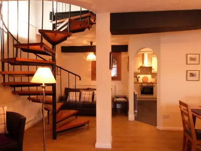 a living room with a spiral staircase and a kitchen at Drws y Nant in Dolgellau