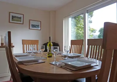 a wooden table with a bottle of wine and glasses at Gerddi'r Coed in Dolgellau