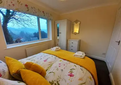 a bedroom with a bed with yellow sheets and a window at Gerddi'r Coed in Dolgellau