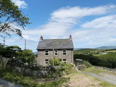an old stone house on the side of a road at Gwarcwm Uchaf in Tre-Taliesin
