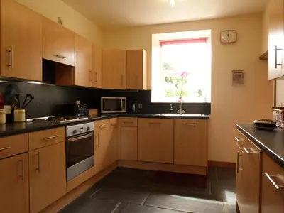 a kitchen with wooden cabinets and a window at Gwarcwm Uchaf in Tre-Taliesin