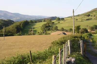 a fence in a field with green hills at Gwarcwm Uchaf in Tre-Taliesin