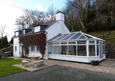 a house with a conservatory with a picnic table in front of it at Ysgubor Illtyd in Dolgellau
