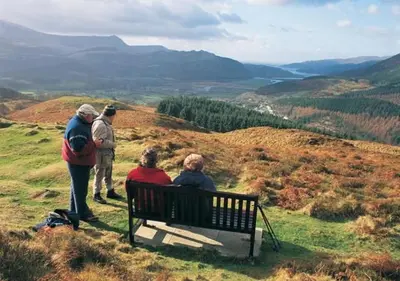 a group of people sitting on a bench on a hill at Ysgubor Illtyd in Dolgellau