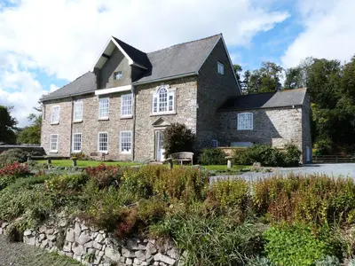 a large stone house with a black roof at Tref y Nant in Castle Caereinion
