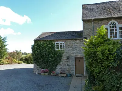 a stone house with a door and a hedge at Tref y Nant in Castle Caereinion