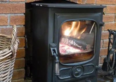 a stove with a fire in a brick fireplace at Ty Clyd in Cross Inn