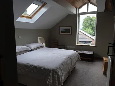 a bedroom with a large bed and two windows at Top House in Welshpool