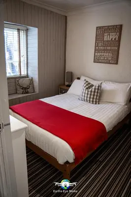 a bedroom with a large bed with a red blanket at The Bear Inn in Llandovery