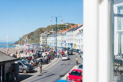 a busy city street with a crowd of people and cars at Sea view Ar Lan y Mor LUXURY APARTMENT in Aberystwyth