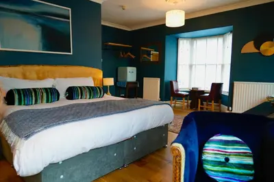 a bedroom with a bed and a dining room at Arosfa Harbourside Aberaeron in Aberaeron