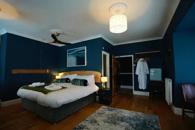 a blue bedroom with a bed and a ceiling fan at Arosfa Harbourside Aberaeron in Aberaeron