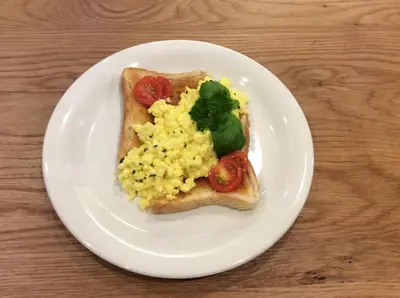 a white plate with a piece of toast with eggs and tomatoes at Ty Mawr at Bethania B&B Rooms and Crumble Cottage in Llanon