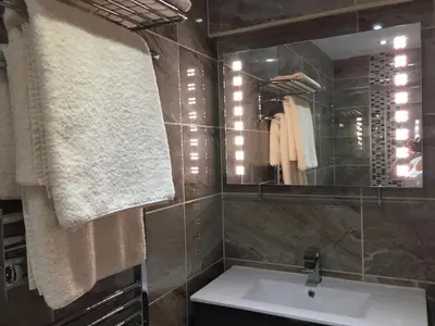 a bathroom with a sink and a mirror and towels at The Town House BnB in Brecon