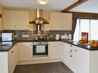 a kitchen with white cabinets and black counter tops at Llaethdy-Milkhouse in Talgarth