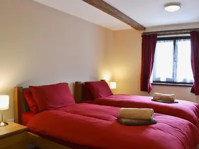 a bedroom with two beds with red sheets and a window at Llaethdy-Milkhouse in Talgarth
