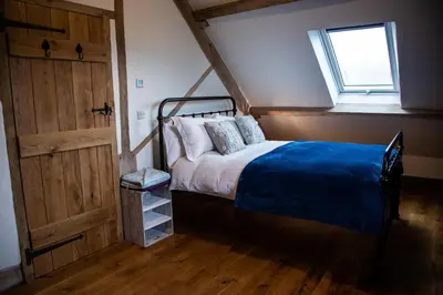 a bedroom with a bed with a blue blanket and a window at Drovers Rest Farm Stay in Hay-on-Wye