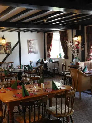 a dining room with tables and chairs with green napkins at The Railway Inn in Forden