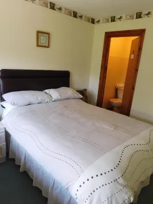a bedroom with a large bed with white sheets at The Railway Inn in Forden