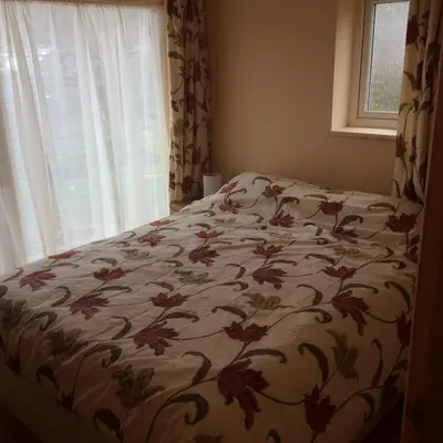 a bed in a bedroom with a floral bedspread at Ty'r Afon - River Cottage in Bala