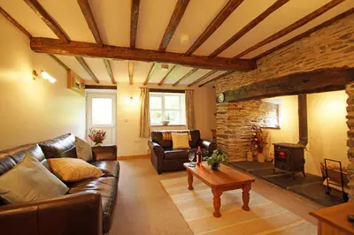 a living room with a leather couch and a fireplace at Hen Gapel in Aberhosan