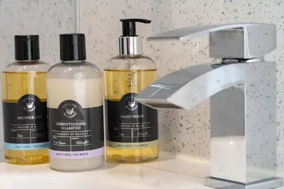 three bottles of oils are sitting next to a faucet at Awel y Mor in Aberdyfi