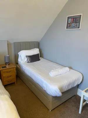 a small bedroom with two beds and a night stand at Bodalwyn Guest House in Aberystwyth