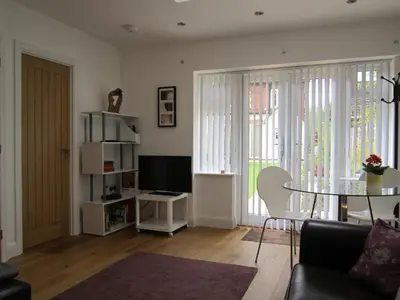 a living room with a table and a television at Temeside Garden House in Ludlow