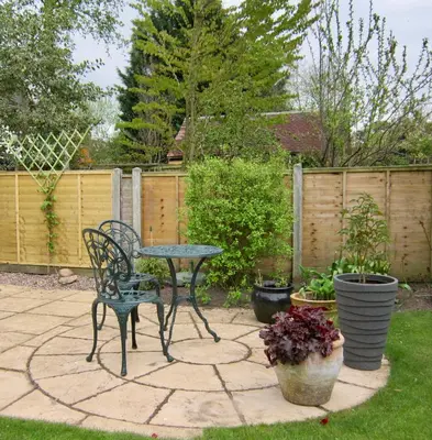 a patio with a table and chairs and potted plants at Temeside Garden House in Ludlow