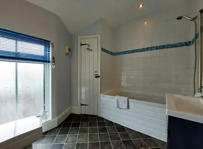 a bathroom with a tub and a shower and a sink at Salt Marsh Apartment in Tywyn