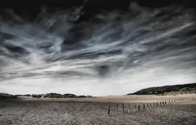 a black and white photo of a beach with a fence at Penrhosmawr in Machynlleth