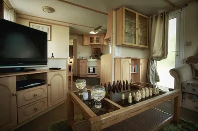 a living room with a tv and a table with wine glasses at Penrhosmawr in Machynlleth