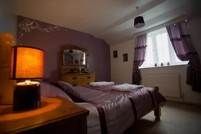 a bedroom with a bed and a lamp and a window at Penrhosmawr in Machynlleth